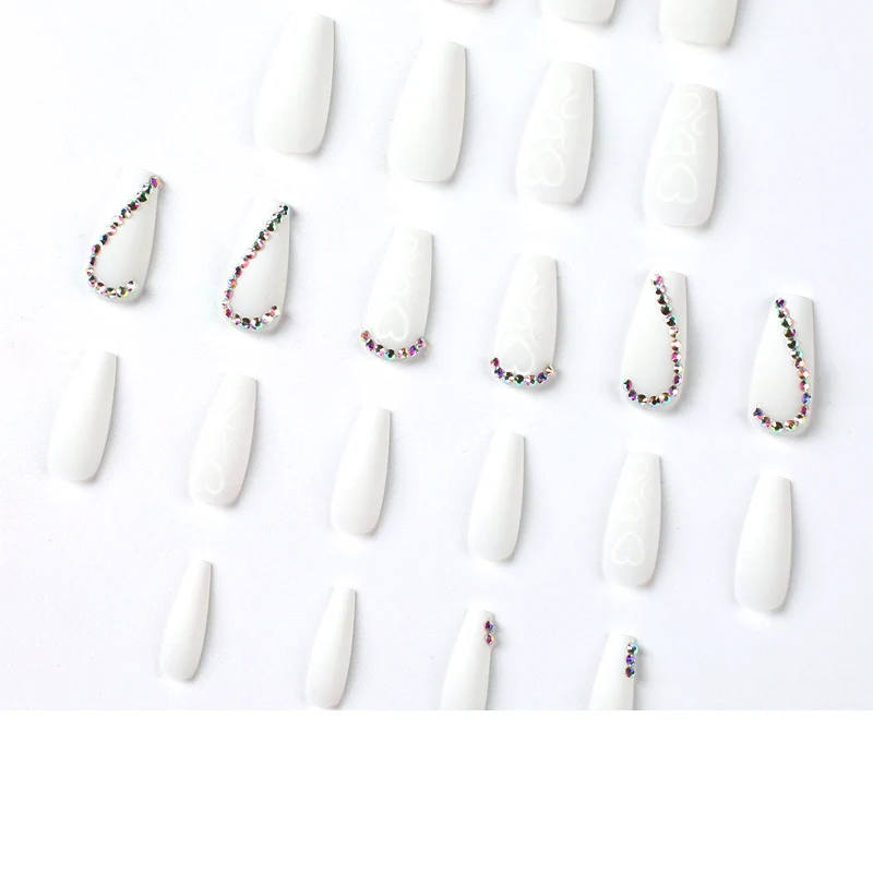 Kunstvolle Nagelverlängerungen mit Herzen-Design und Glitzerakzenten Karnz