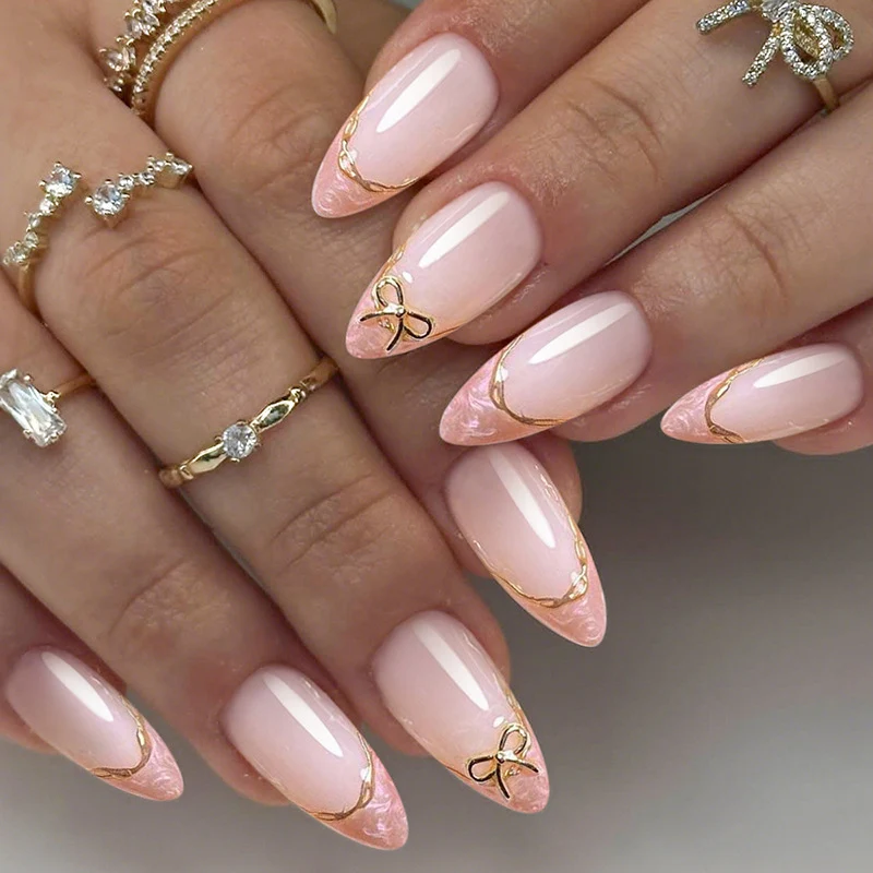 Kunstnagelset mit zarten Schleifen- und goldenen Akzenten Karnz